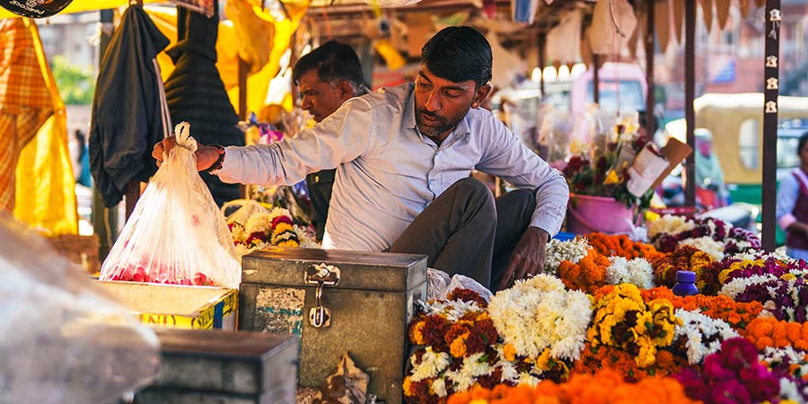 A vendor sits at his stall holding a bag. 
